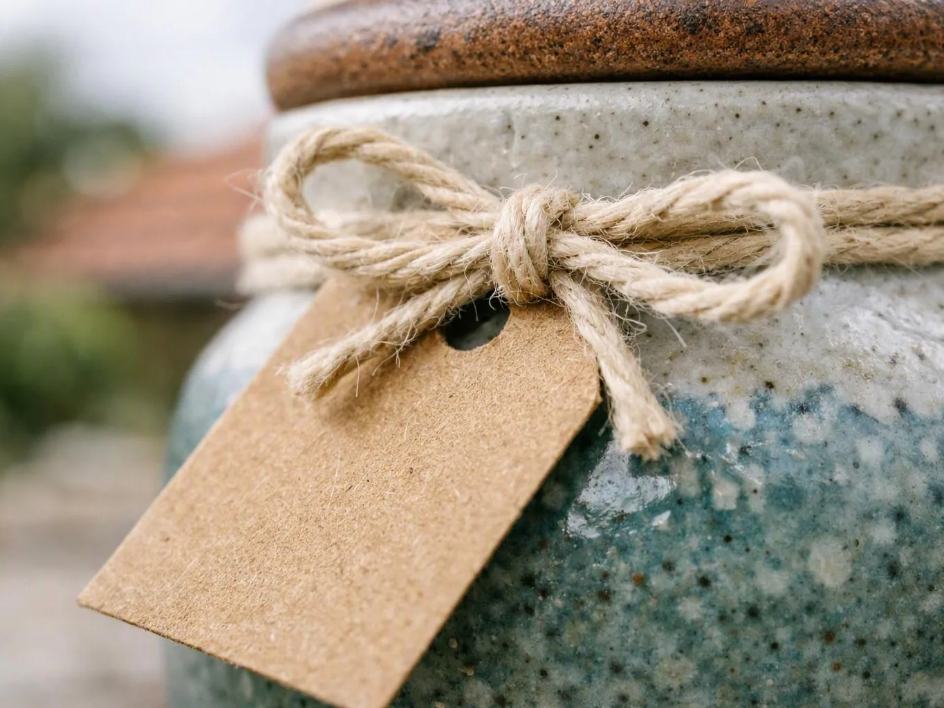 A close-up shows a speckled ceramic jar tied with twine and a blank paper tag